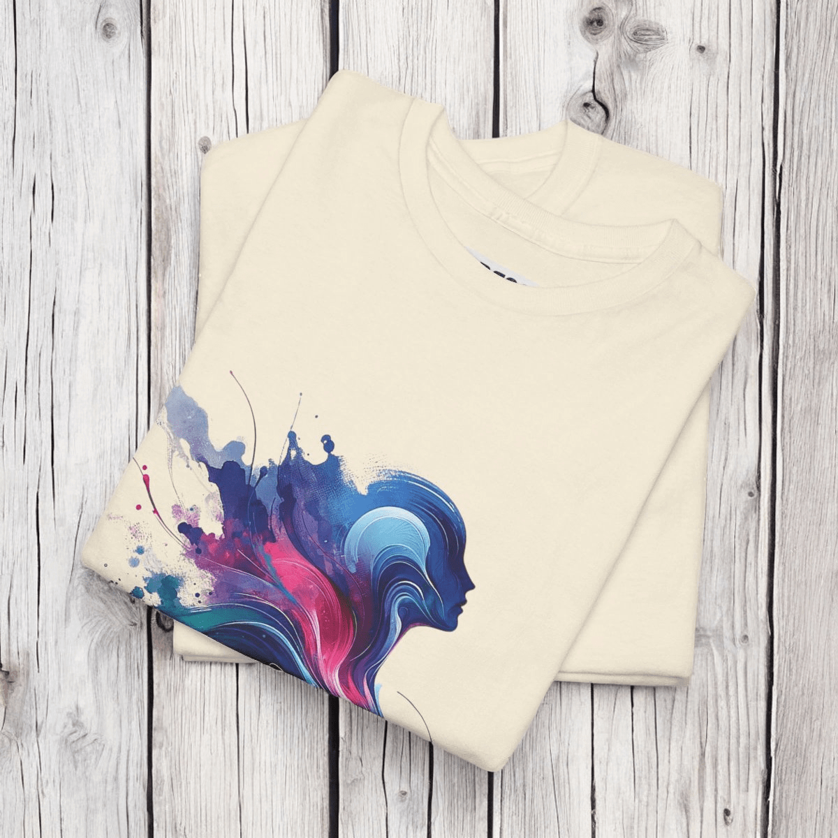 Folded Natural tee with striking multicolor abstract design on a wood surface