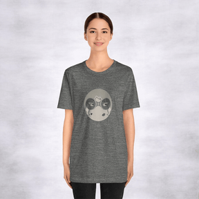 Woman in gray tee featuring circular, stylized face design with abstract mountain, moon elements, white backdrop