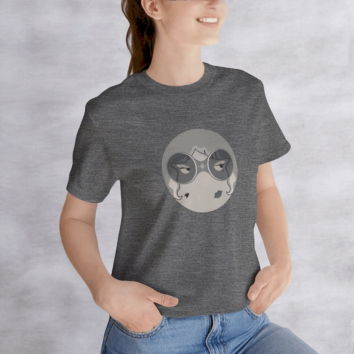 Smiling person in gray tee featuring illustrated face design with stylized eyes and lips on gray surface