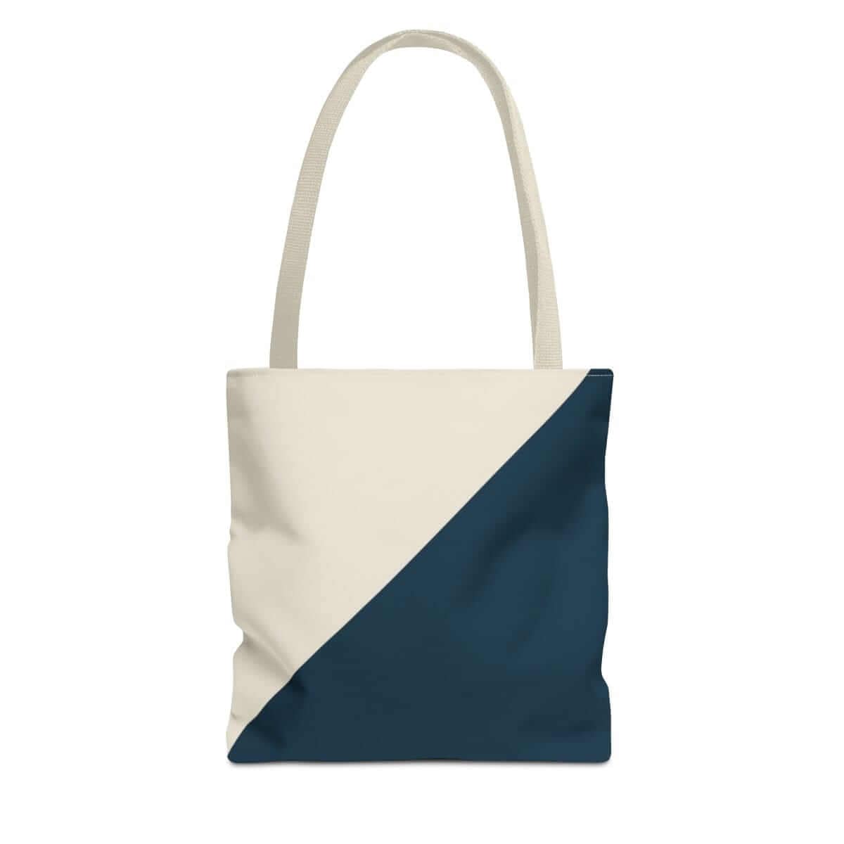 Cream and navy canvas tote bag with diagonal color block design and wide shoulder straps in minimalist style