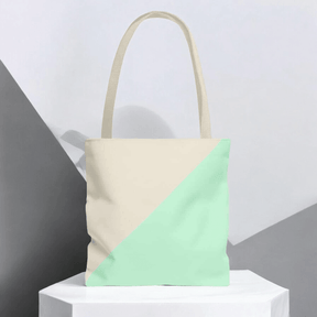 Beige and teal canvas tote bag with geometric panel design and minimalist straps on neutral background surface