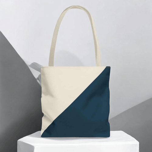 Beige and dark teal tote bag with diagonal design against a minimalist gray and white backdrop