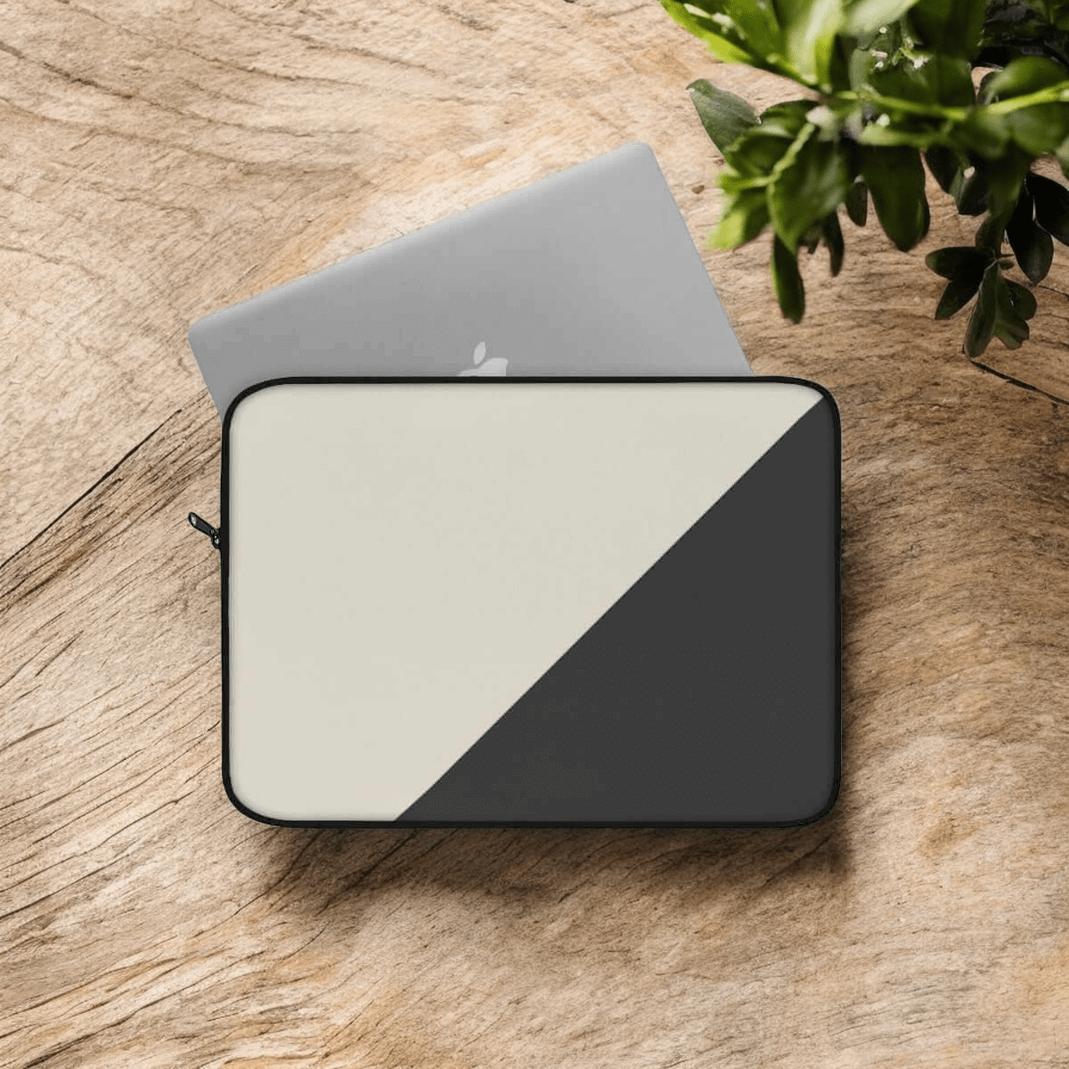 Laptop sleeve with beige and black diagonal color block design made from fabric, partially covering a silver laptop