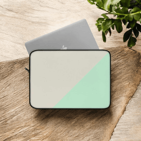 Laptop sleeve in beige canvas with mint green bottom section, minimalist style and zipper closure on wooden surface