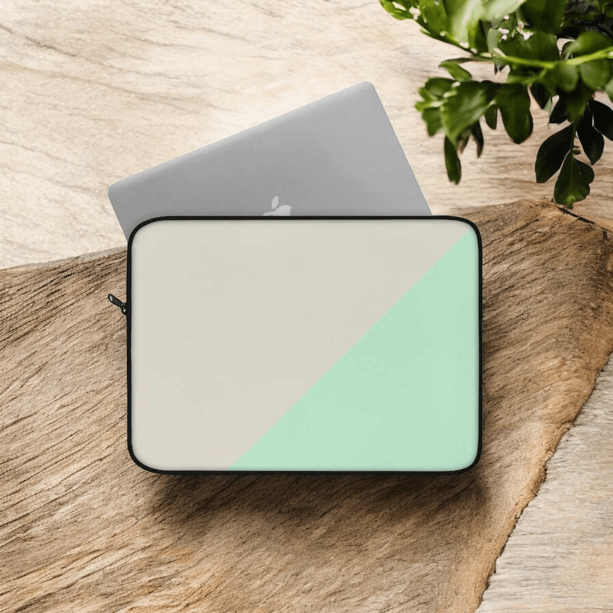 Laptop sleeve in beige canvas with mint green bottom section, minimalist style and zipper closure on wooden surface
