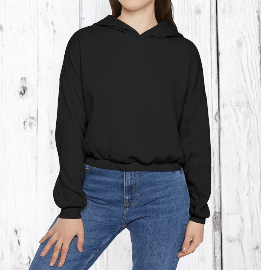 Black cotton hoodie with relaxed fit and ribbed cuffs worn with casual blue jeans against white wooden backdrop