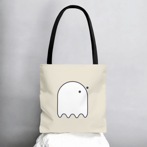 Beige tote bag with cartoon-like white ghost outline and black handles in minimalist style