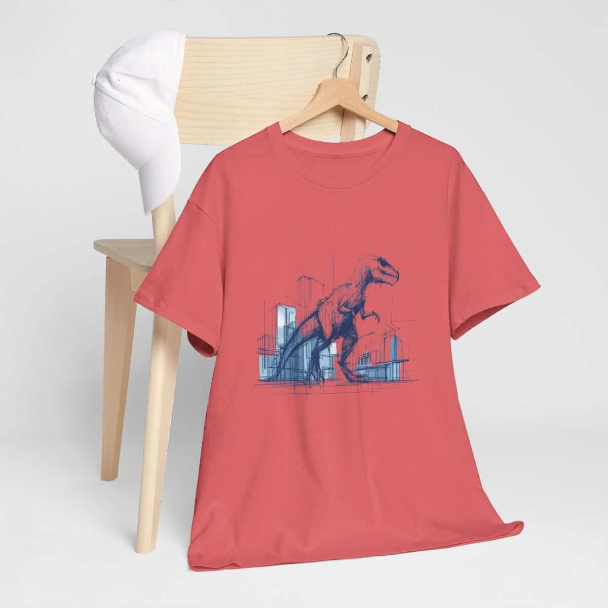 Red cotton short sleeve t-shirt featuring a blue dinosaur sketch design, casually draped over a chair beside a white cap