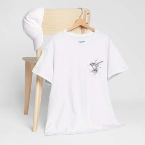 White cotton t-shirt with minimalist bird graphic and plain white cap displayed on a wooden chair with neutral background