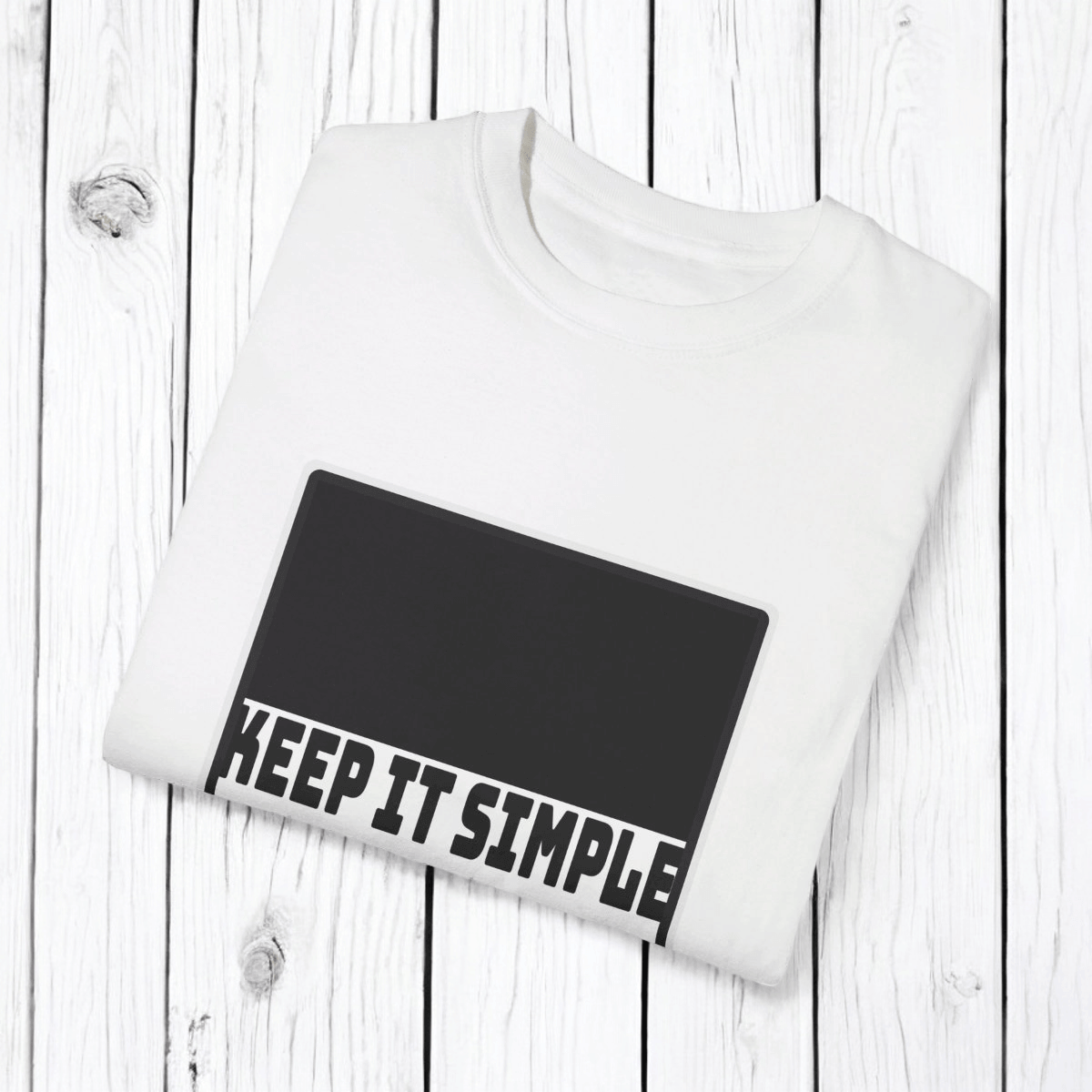 White cotton T-shirt with minimalist black text design reading 'KEEP IT SIMPLE' displayed on a wooden surface
