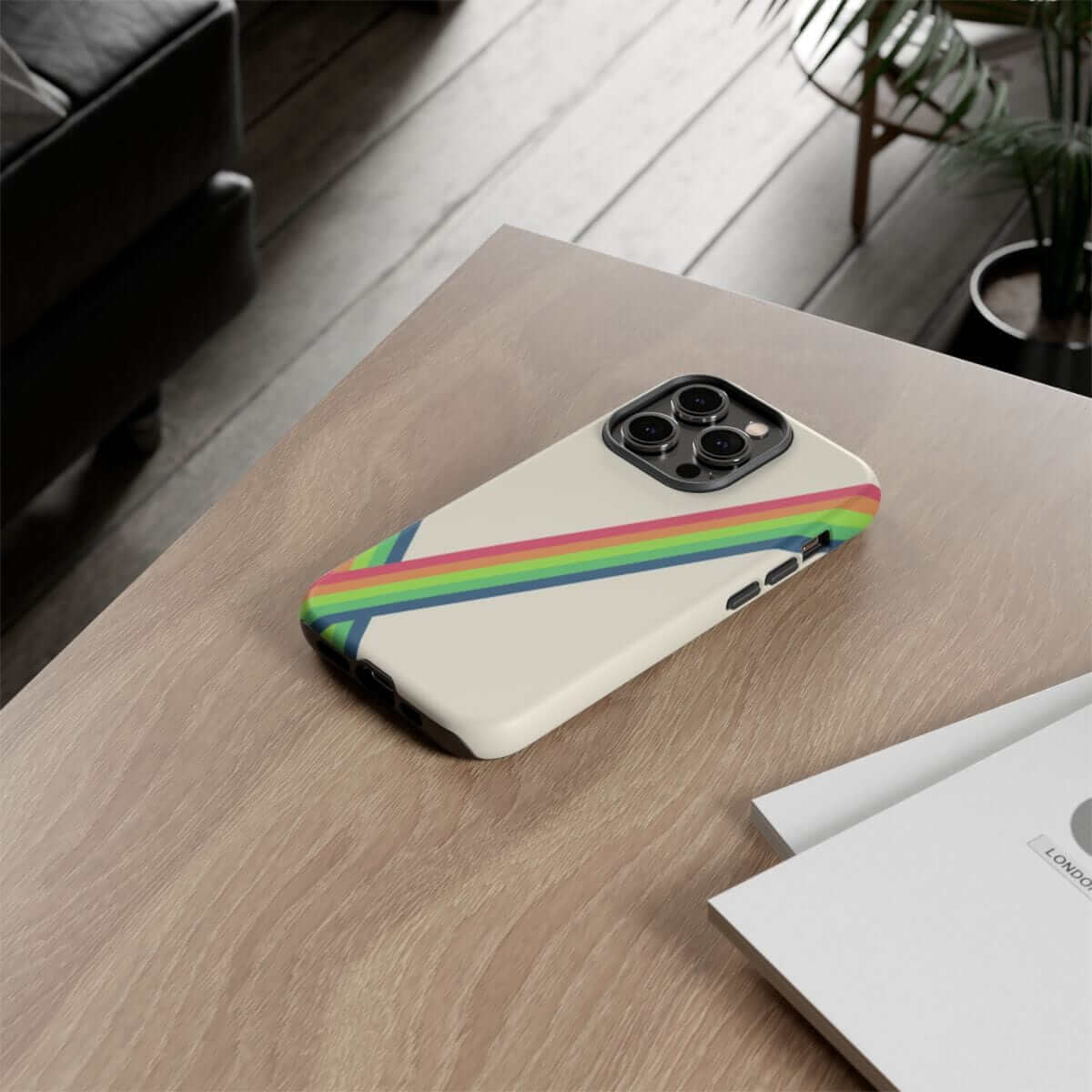 Phone case with red and rainbow stripes in glossy plastic finish resting on a wood table beside printed documents