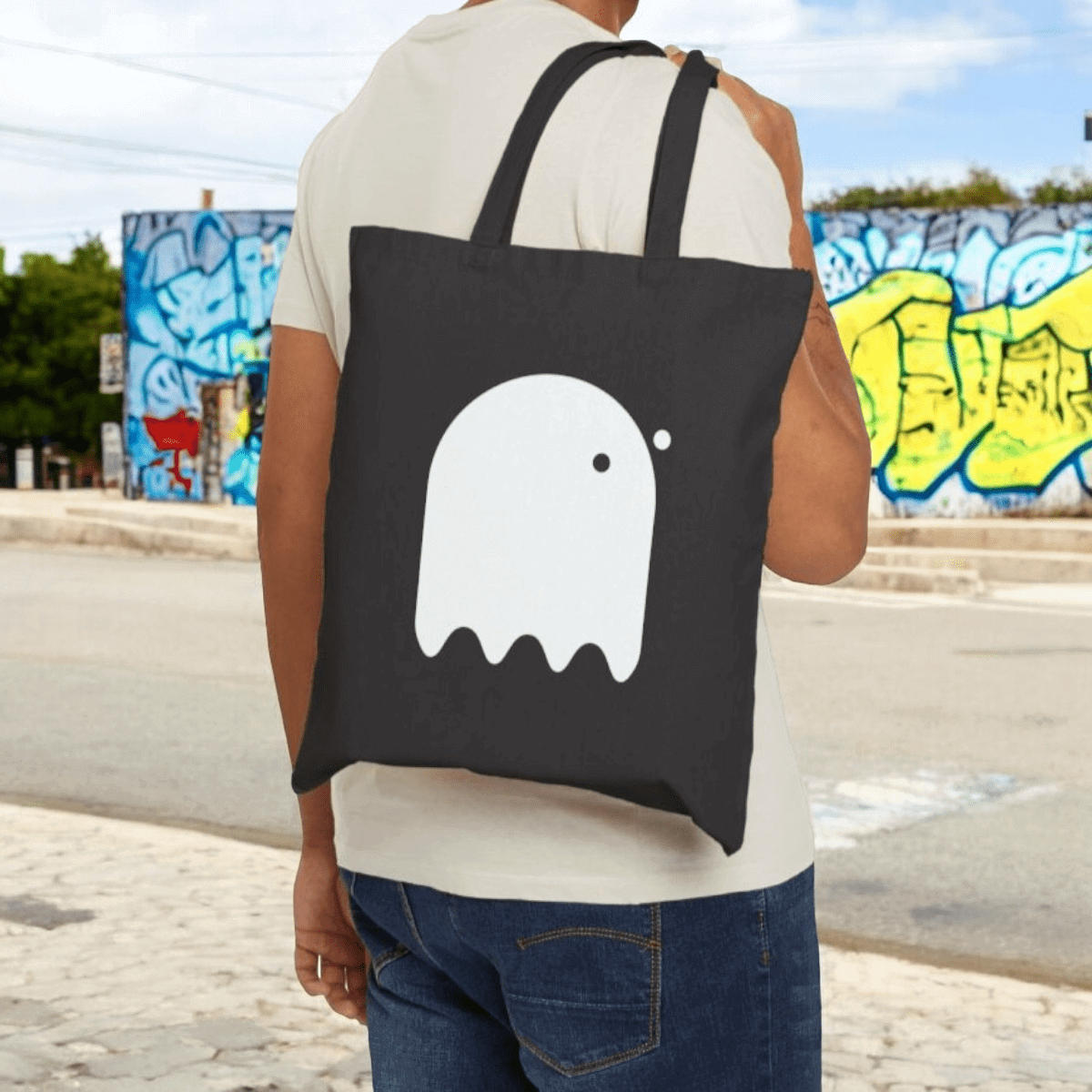 White canvas tote bag with black graphic print featuring a ghost design, sturdy handles, and a rectangular shape